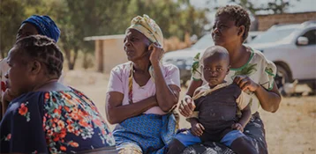 Black women sitting and one has a child on her lap