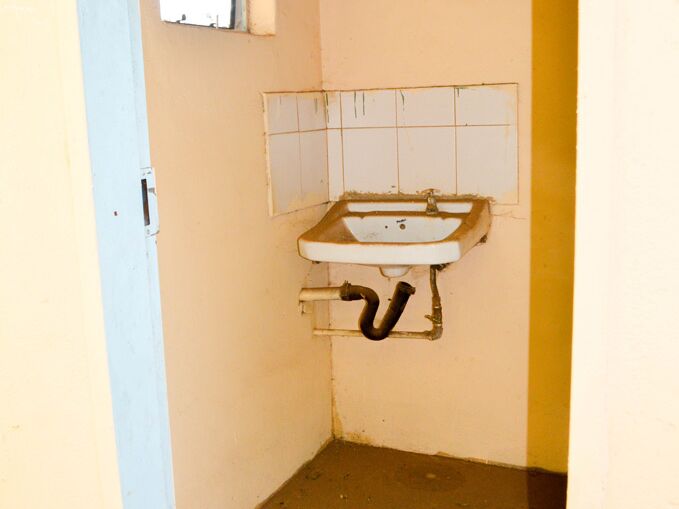 A small bathroom with a broken sink and a small window.